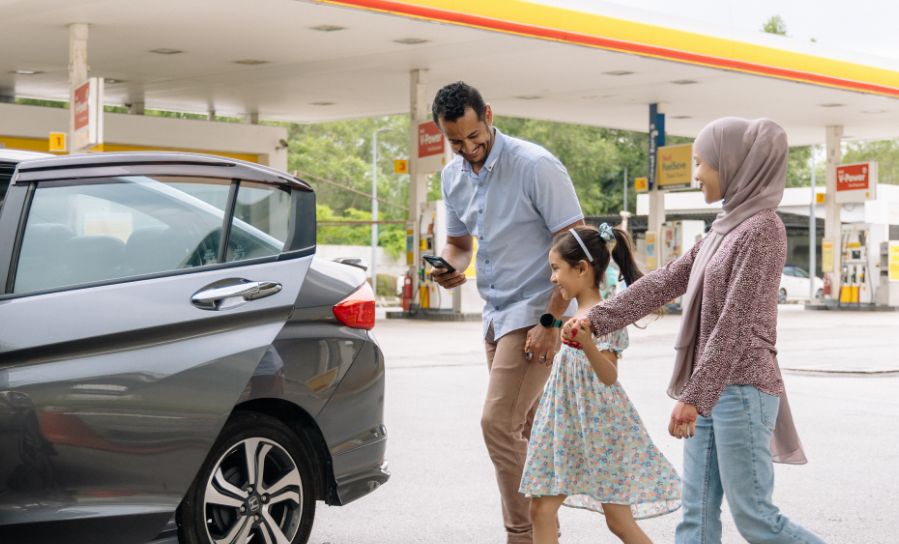 Happy family preparing to enter rental car at petrol station
